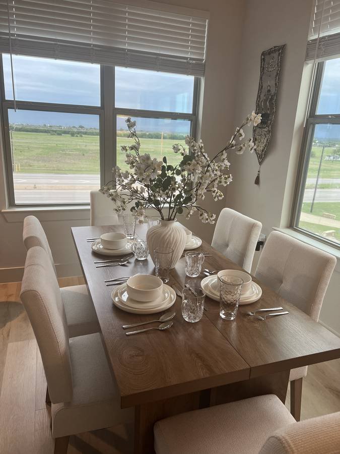 A dining table set with cream plates, glassware and blossom for guests